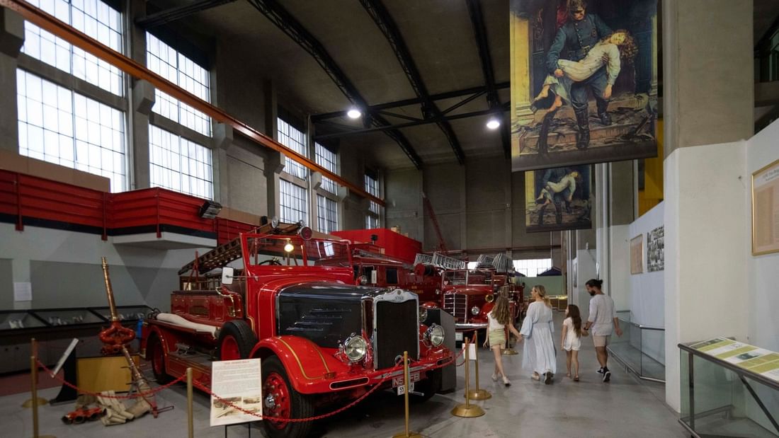 People walking by historic fire trucks on display at the Museum of Fire.