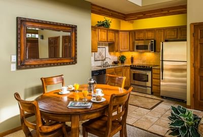 A rustic kitchen and dining area at The Stanley Hotel with a wooden table set for breakfast and warm lighting