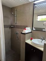 Rolled white towels with red flowers by a white sink under a walk-in shower at Warwick Hotels & Resorts