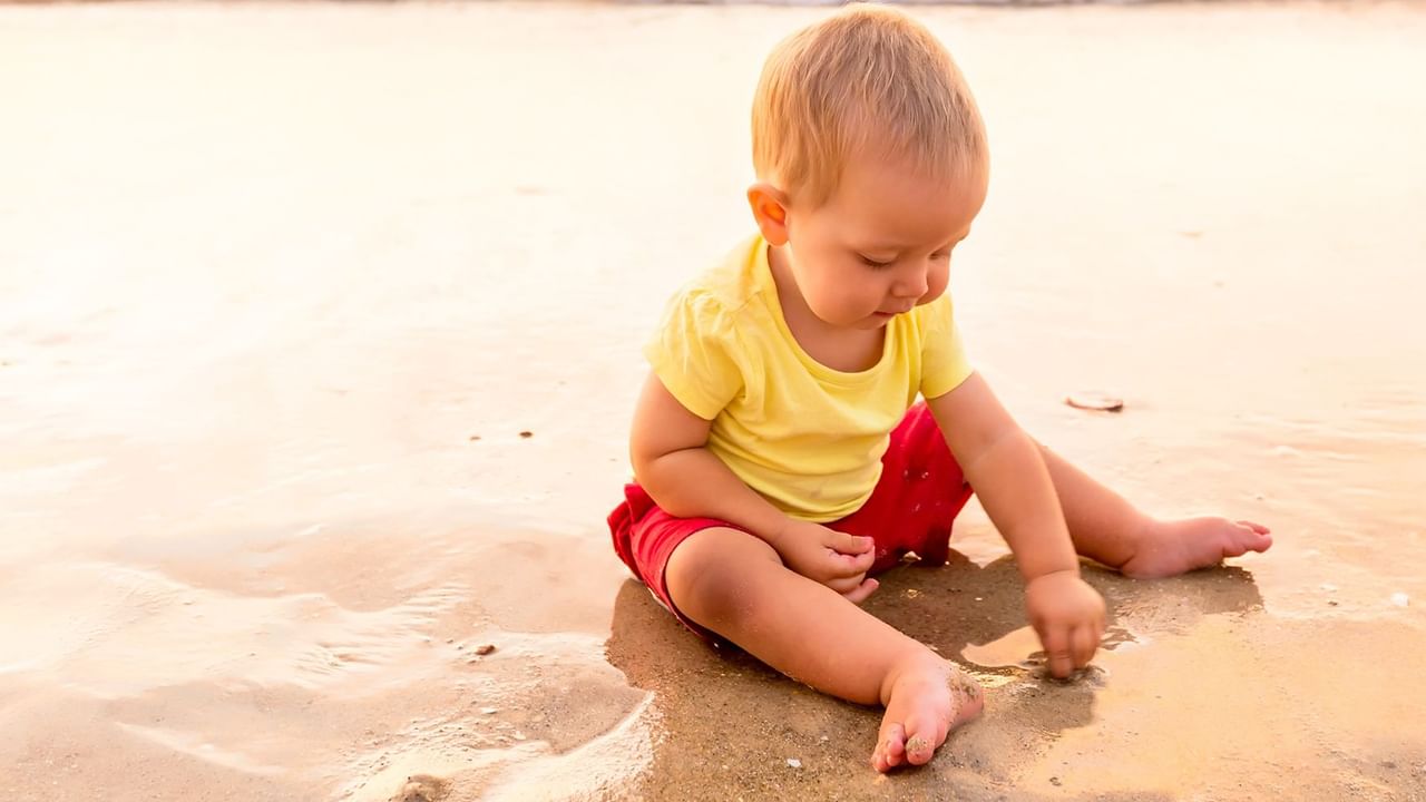 child sitting and playing in wet sand