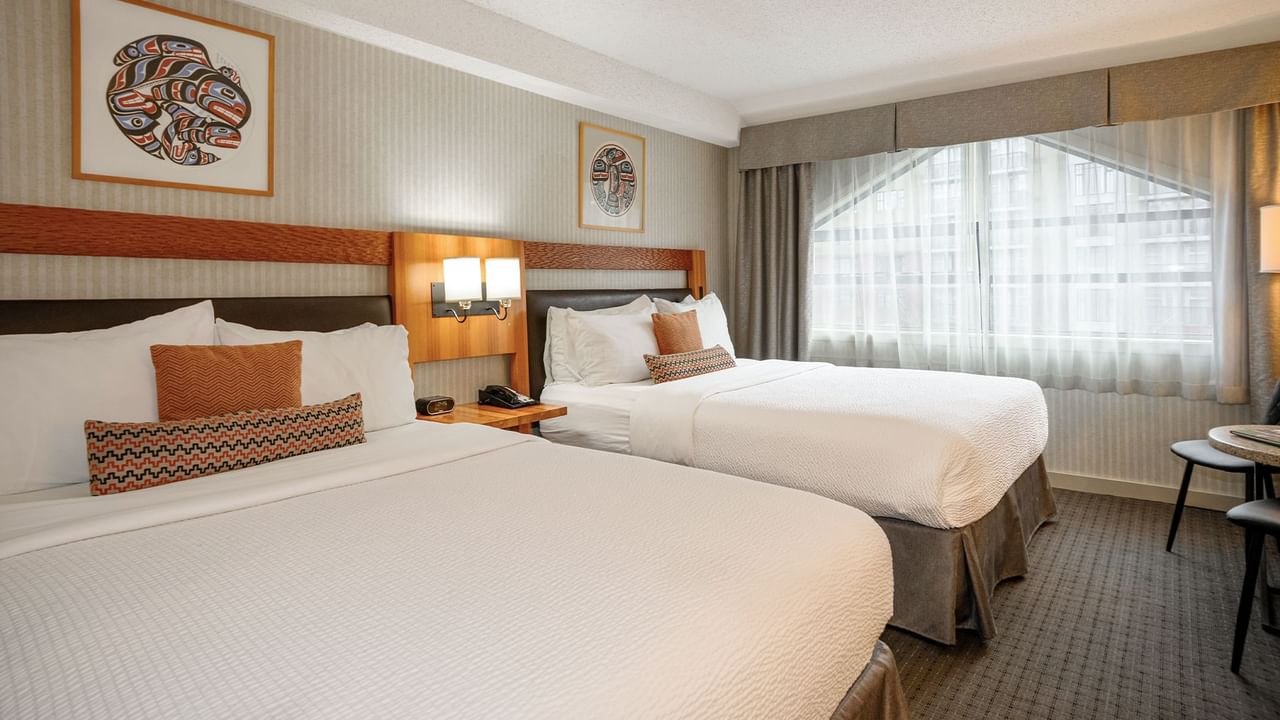 Spacious hotel room with two queen beds, elegant decor and large window for natural light.