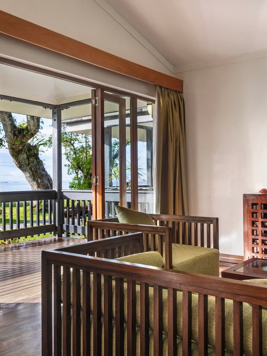 Wooden furniture by a TV under soft light near a balcony in One-Bedroom Villa at The Naviti Resort - Fiji