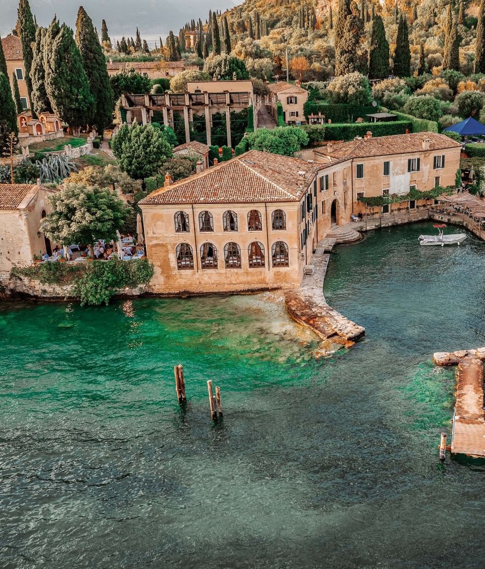 Aerial view of historic stone villa Locanda San Vigilio surrounded by green waters on Lake Garda near Meraviglia