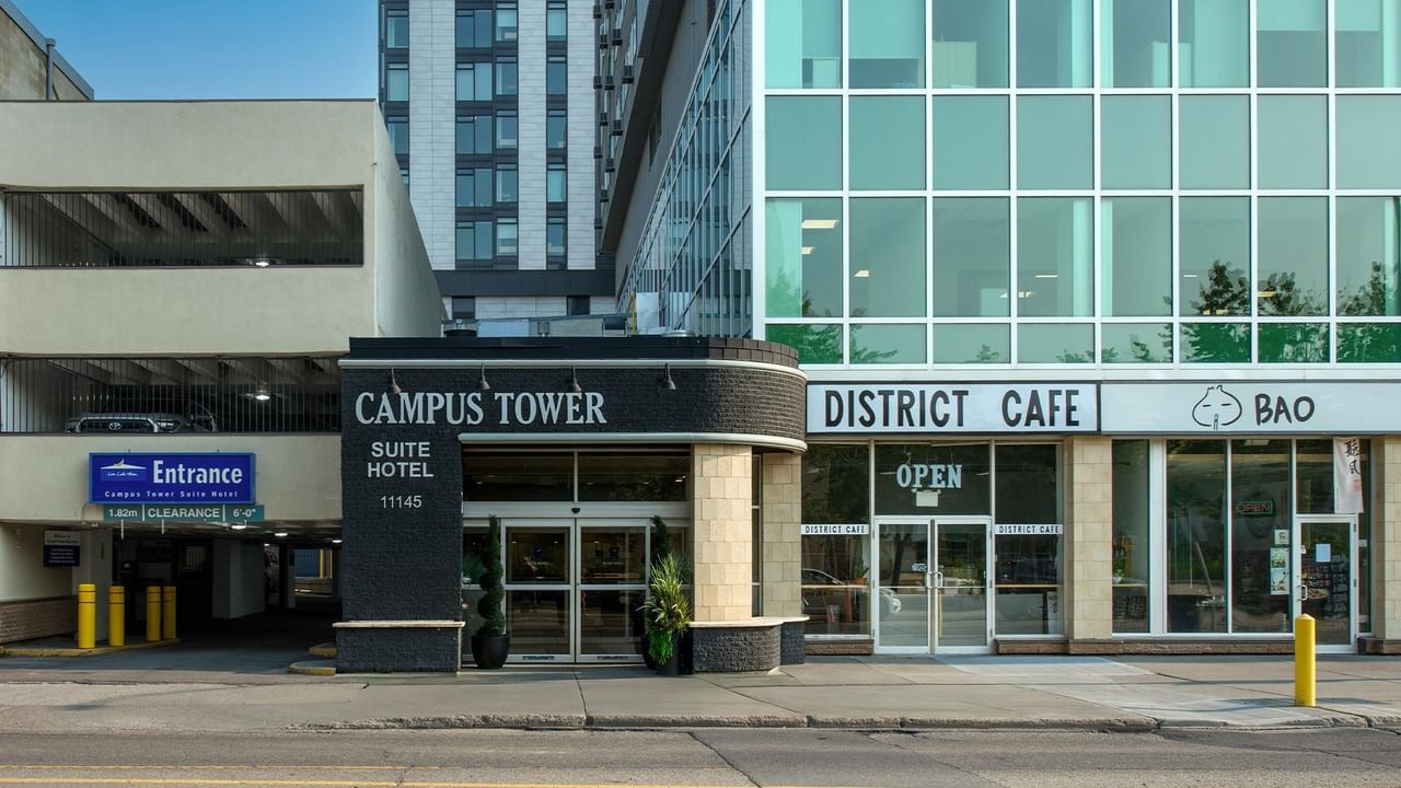 Exterior entrance to Campus Tower Suite Hotel with nearby shops and businesses.
