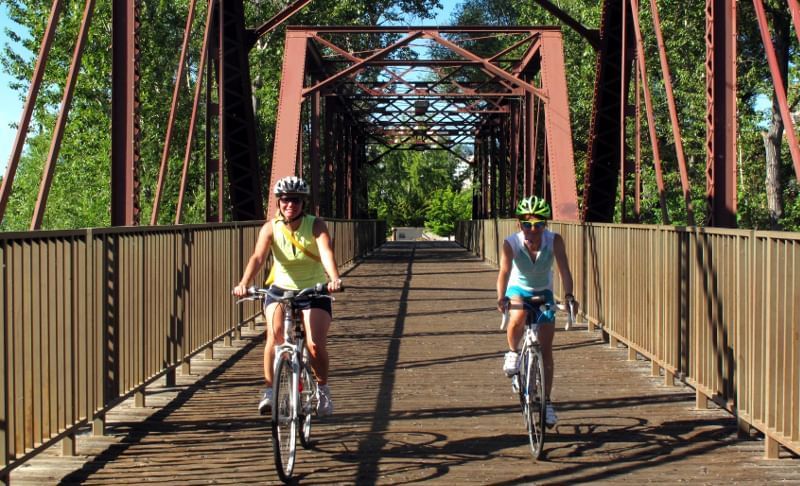 Two people riding bikes across a bridge near Hotel 43