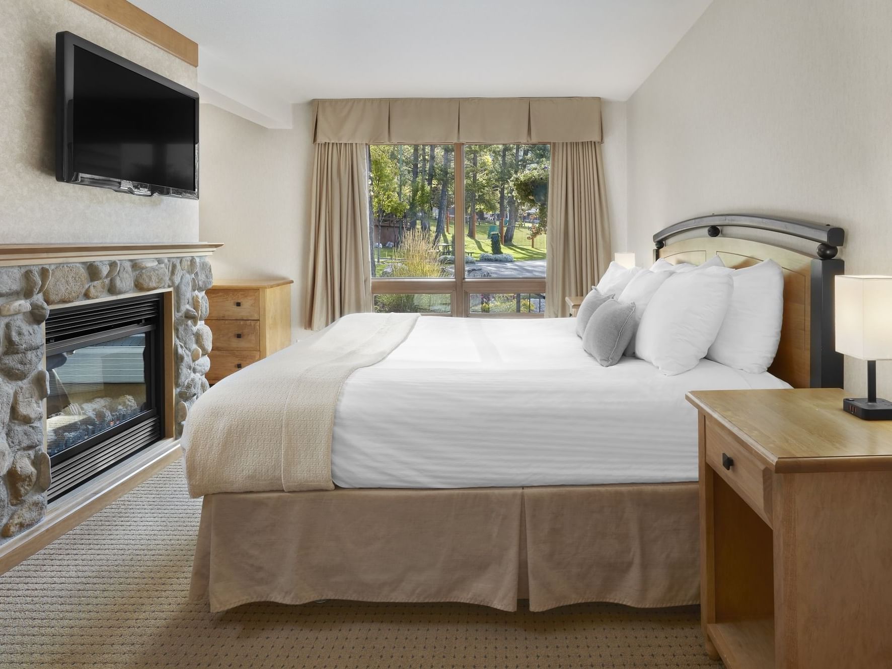 Cozy bed arranged with TV in Pool Facing King Suite at Fairmont Hot Springs Resort