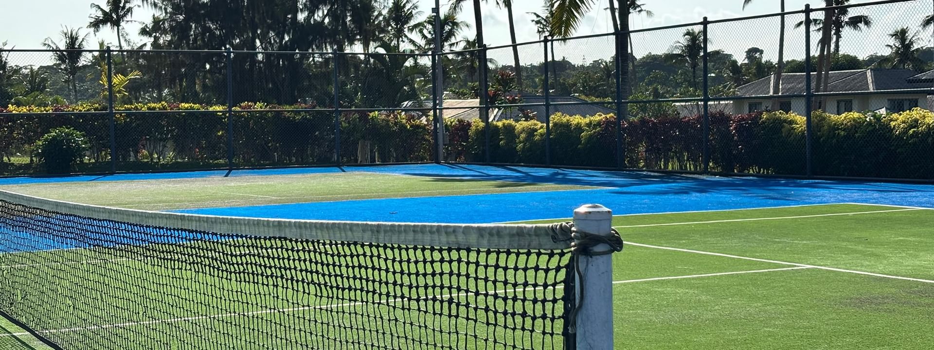 Tennis court with blue and green surface and net at Warwick Le Lagon - Vanuatu in Efate