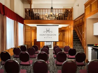 Conference-style meeting room set up with a projector screen at Huntingdon Manor