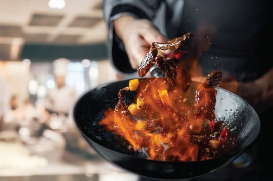 Close-up of chef preparing a dish on a wok at Federal Hotels International
