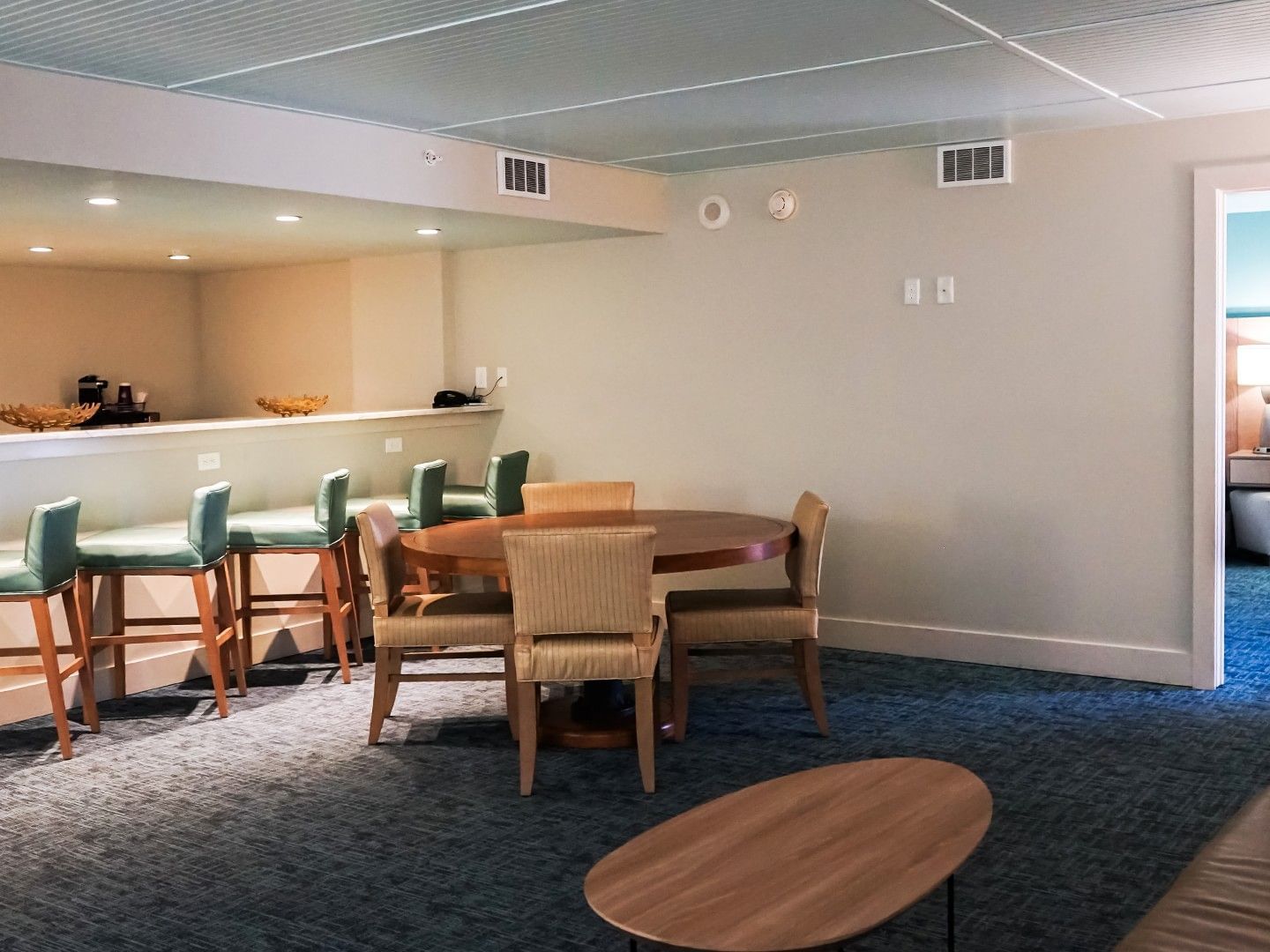 Entertainer Suite featuring a round wooden table and a bar with teal high-back stools at Margaritaville Resort Biloxi
