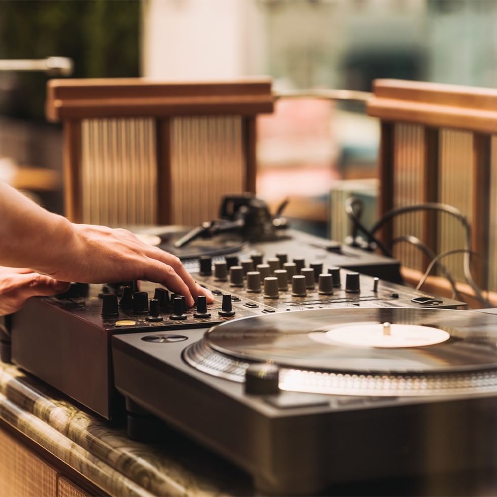 Hand bedient einen DJ-Mixer mit Plattenspielern in einem Café-Ambiente.