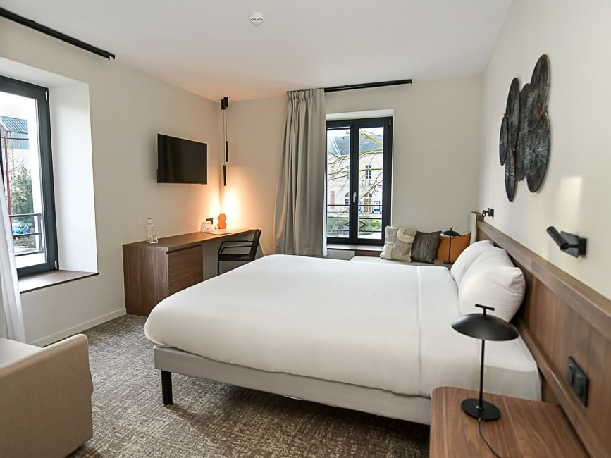 Chambre élégante avec lit double, bureau et vue sur l'extérieur à Hôtel Rivella.