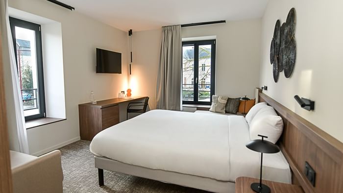 Chambre élégante avec lit double, bureau et vue sur l'extérieur à Hôtel Rivella.