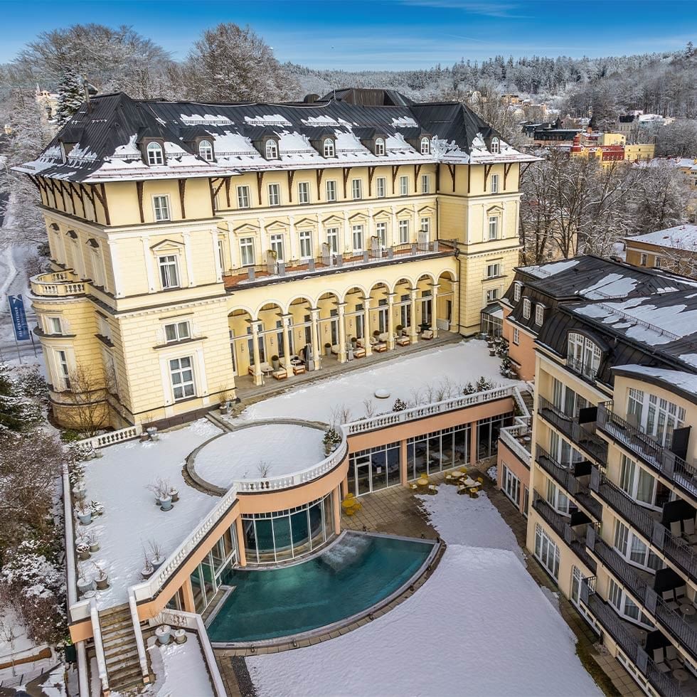 Vista aerea invernale del Falkensteiner Spa Resort Mariánské Lázně con piscina coperta.