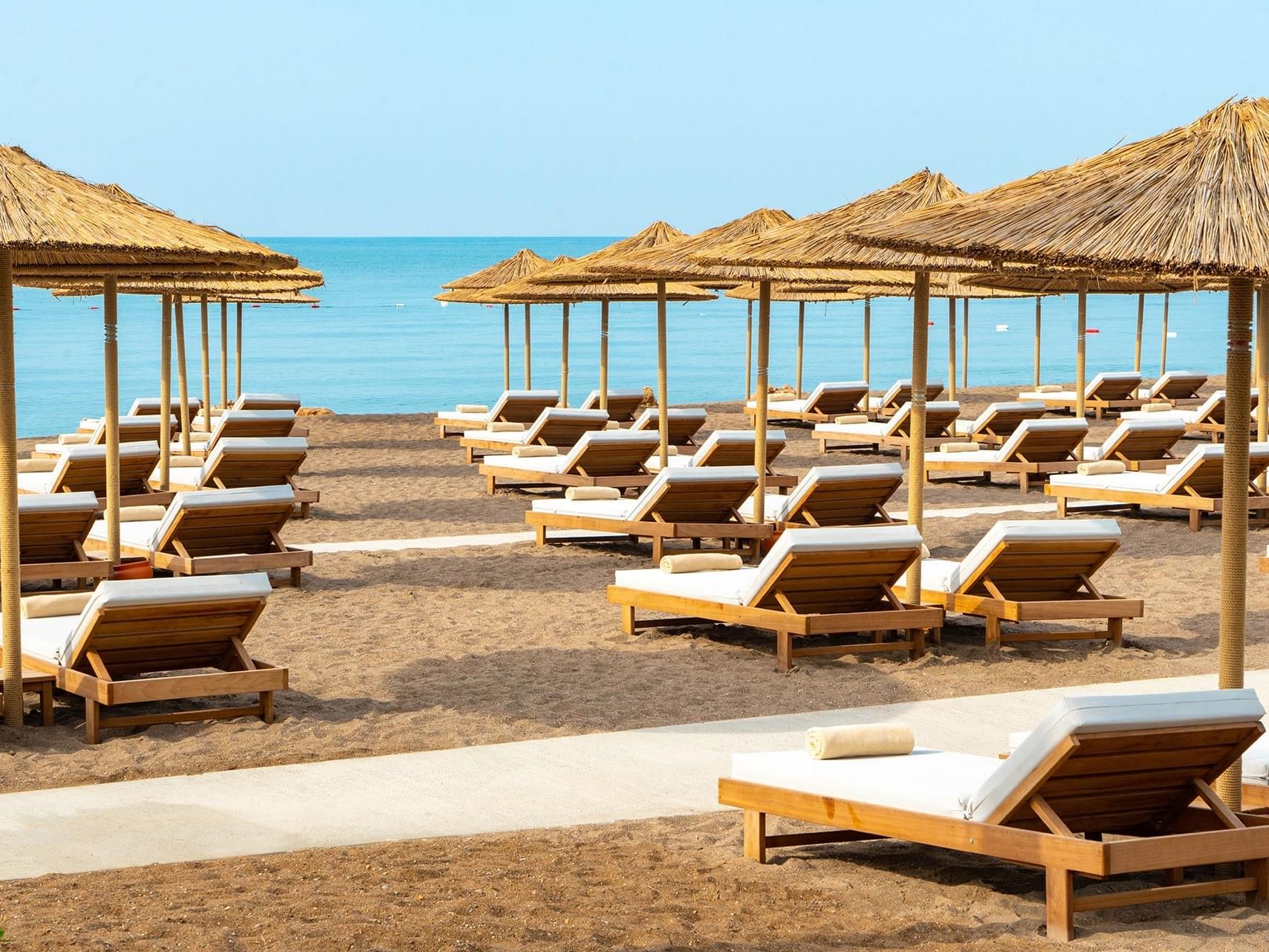 Sun loungers lined up under beach huts and overlooking Lara Beach near Titanic Deluxe Lara