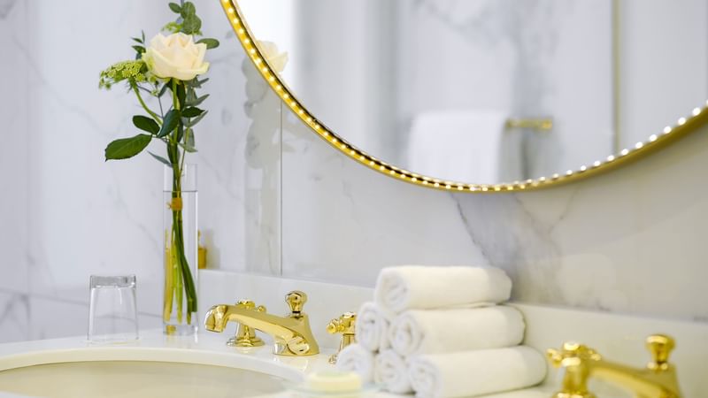 Duke of Westminster Suite bathroom featuring marble walls, golden faucets, towels, and a round mirror at Hôtel Westminster - Paris