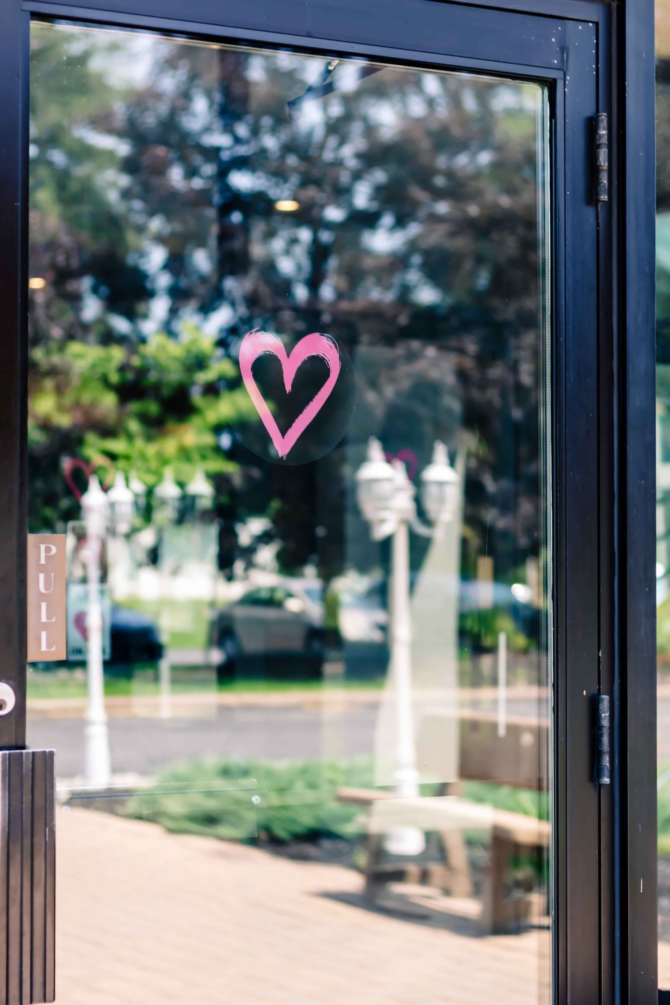 Pink heart display on a glass door, with greenery in the background at Cove Pocono Resorts