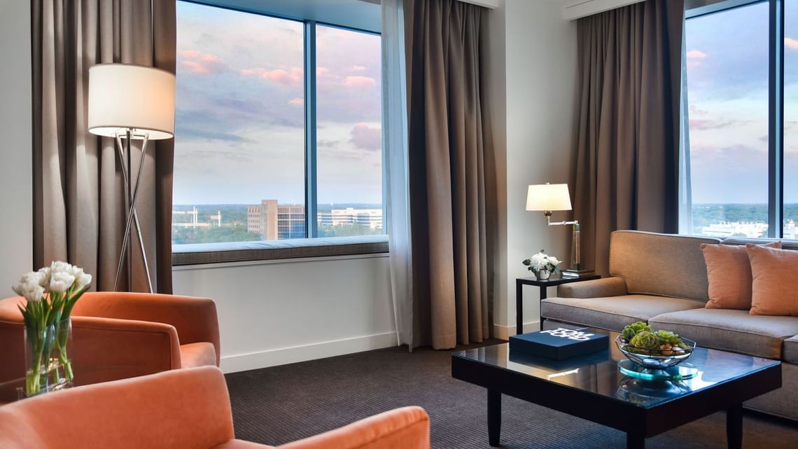 Hotel living room with sofa, chairs, and large windows
