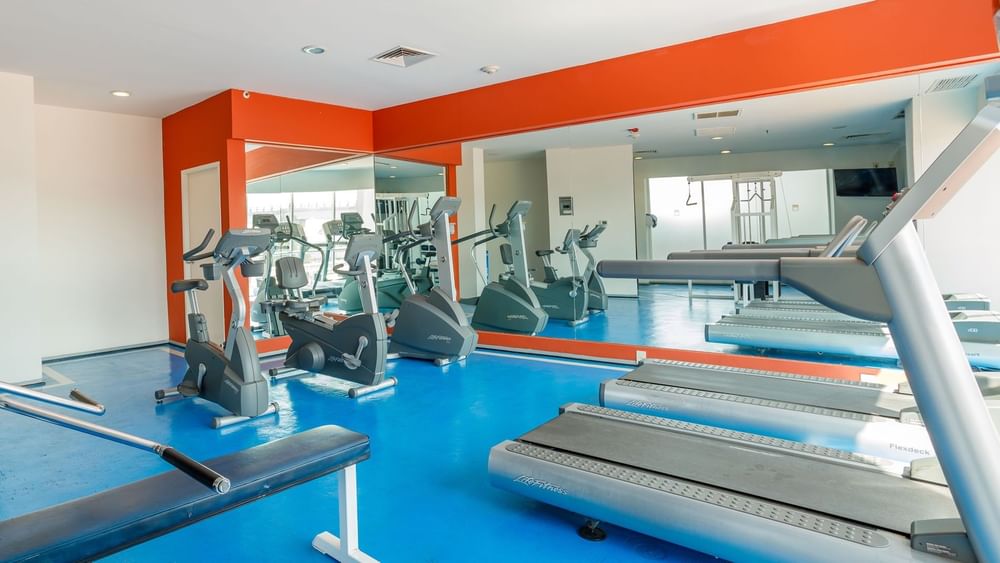 Well-equipped fitness center with treadmills, bikes, and bright blue flooring at Camino Real Pachuca