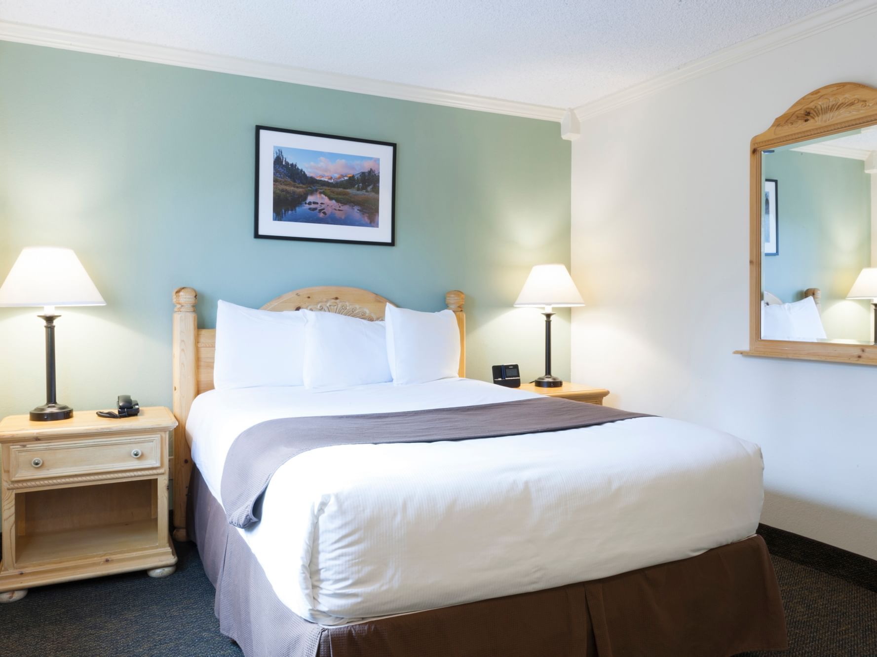 Comfy bed and mirror on wall in Queen Room at Alpenhof Lodge