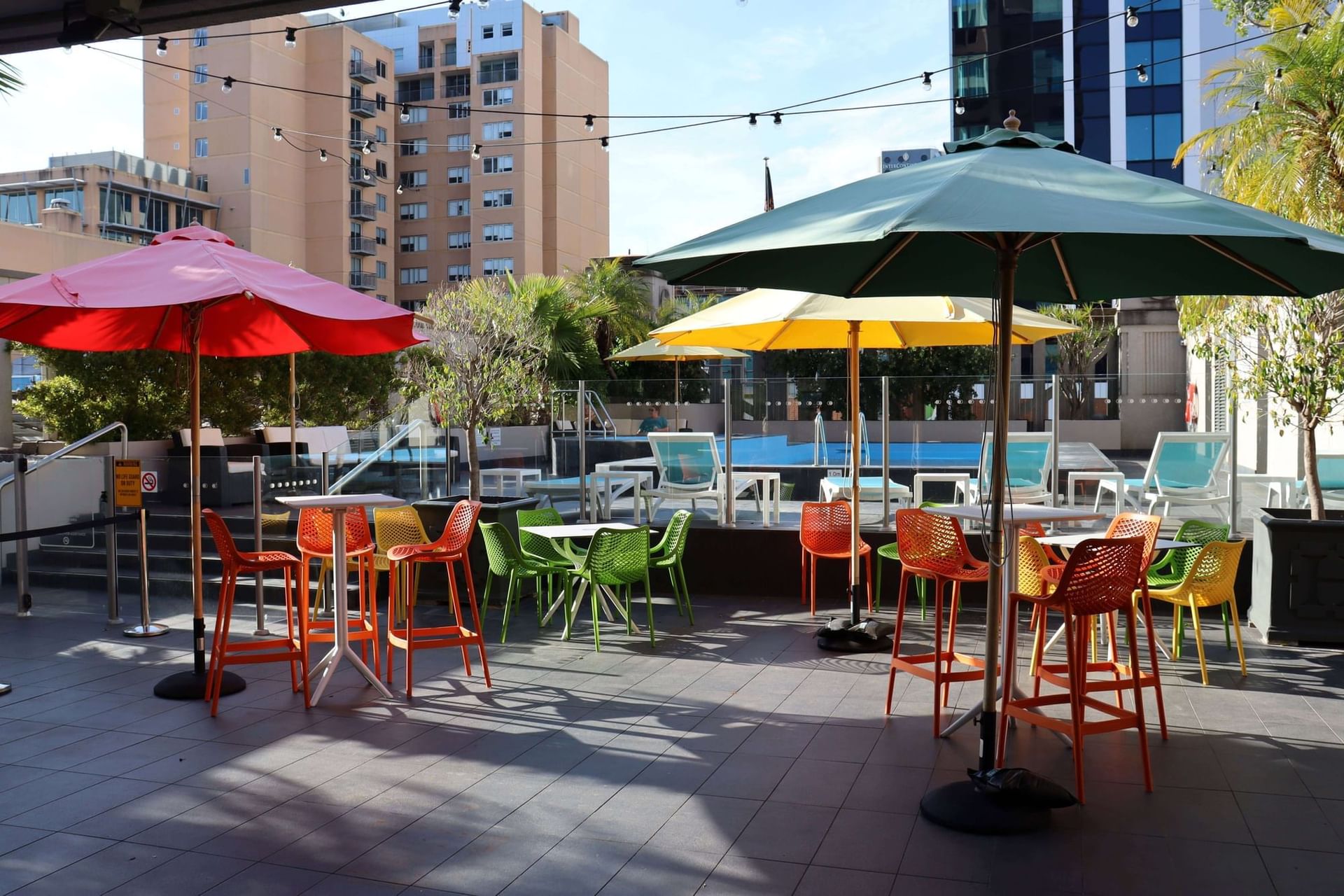 Colorful chairs and umbrellas in outdoor space in poolside at Hotel Grand Chancellor Adelaide