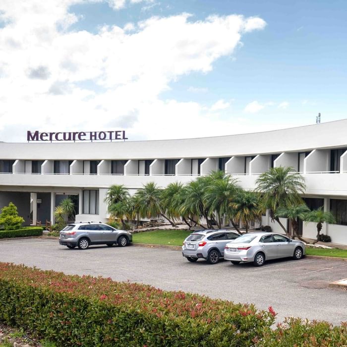 Four cars parked in front of Mercure Hotel in a tropical setting.