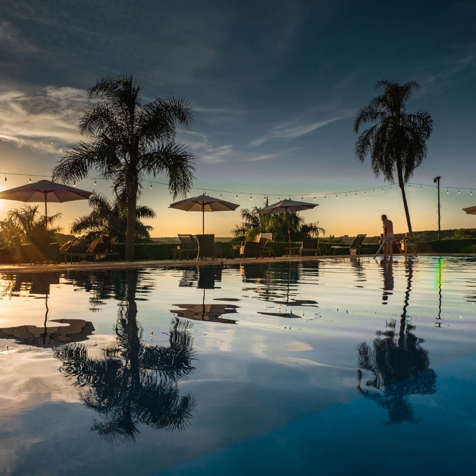 El área de la piscina con cabañas de piscina en Panoramic Grand durante la puesta de sol