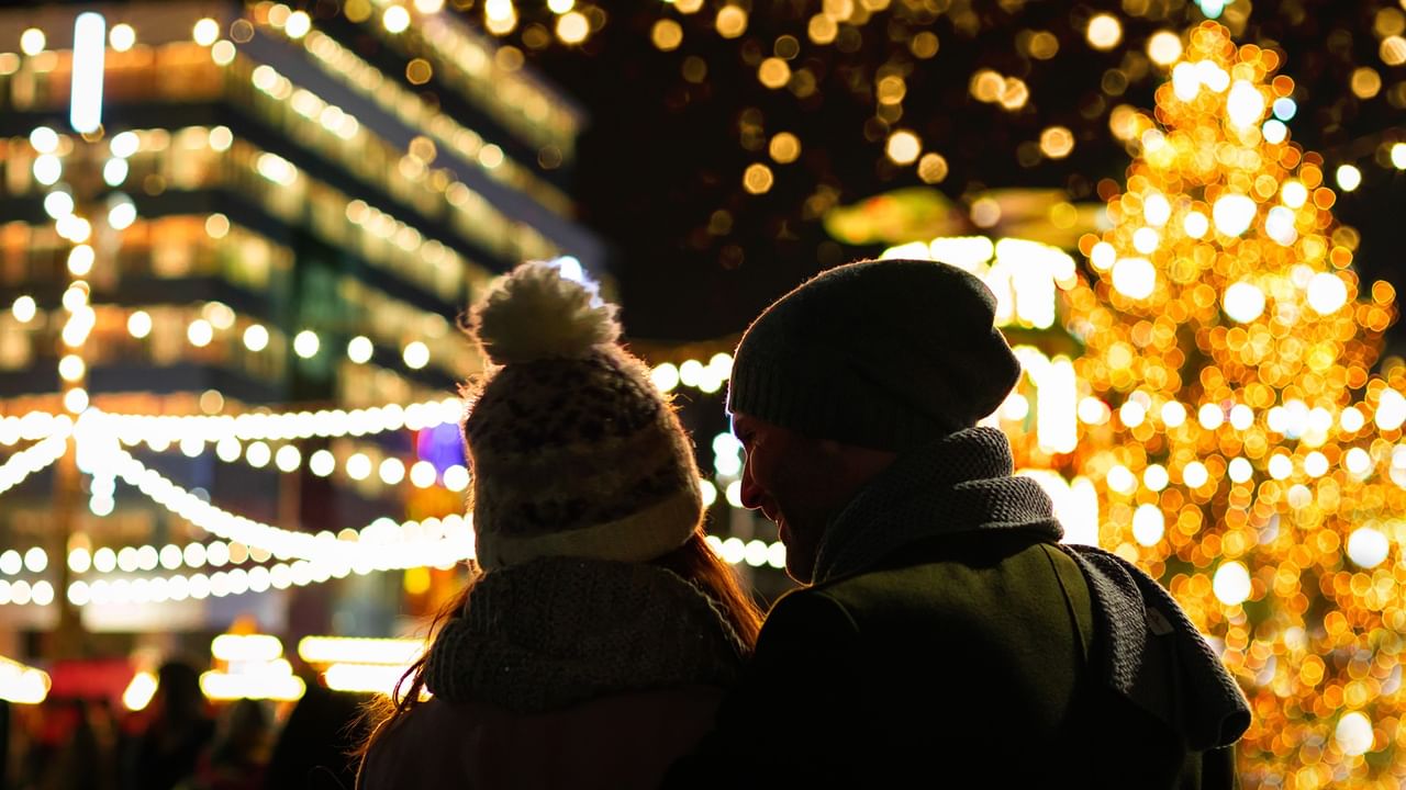 Couple viewing illuminated Christmas tree and festive lights at Milner Christmas Magic outdoor holiday event