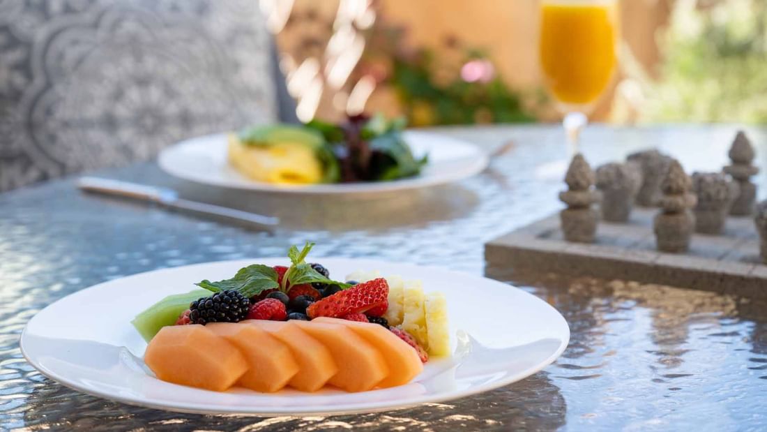 Fresh fruit platter and drinks from the Breakfast in Bed Package at El Prado Hotel, on a patio table
