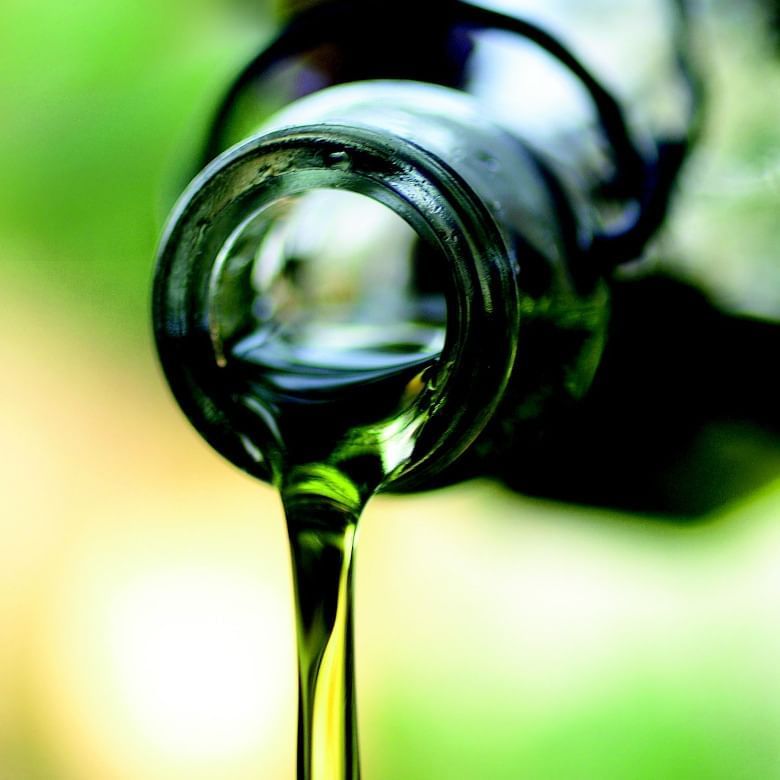Green liquid pouring from a bottle neck, with a blurred green background.