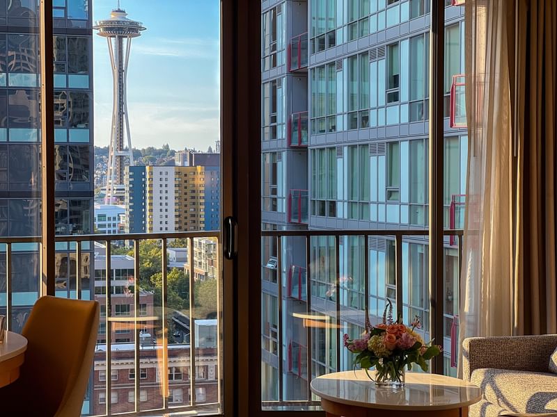 View of the Space Needle by modern buildings under a blue sky from a window in Premier Room at Warwick Seattle