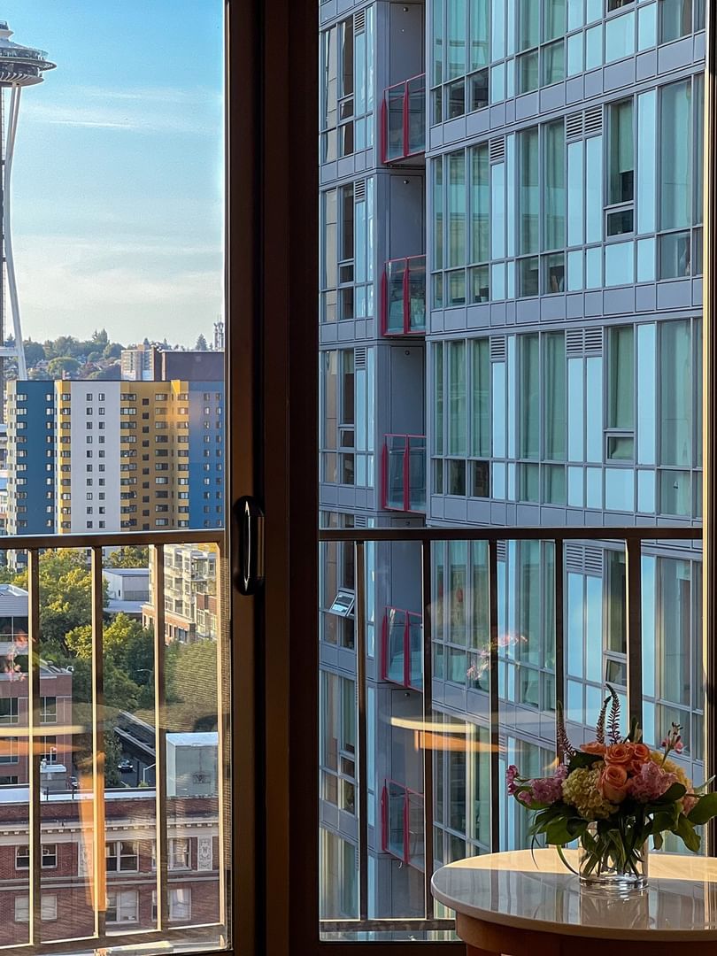 View of the Space Needle by modern buildings under a blue sky from a window in Premier Room at Warwick Seattle
