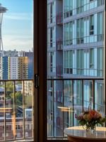 View of the Space Needle by modern buildings under a blue sky from a window in Premier Room at Warwick Seattle