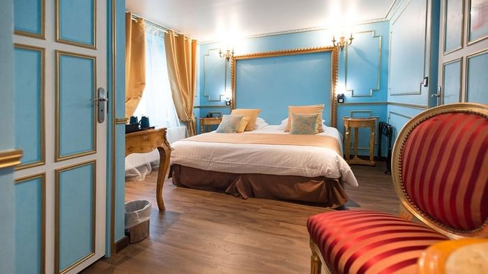 Chambre élégante avec lit et fauteuil rouge à l'Hôtel Villa Aultia.