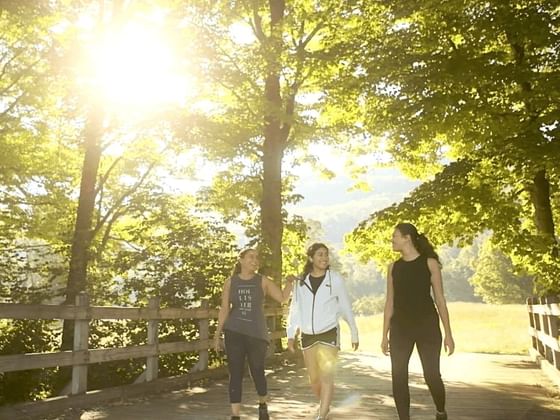 Three women walking on a sunlit path at Honor’s Haven Retreat