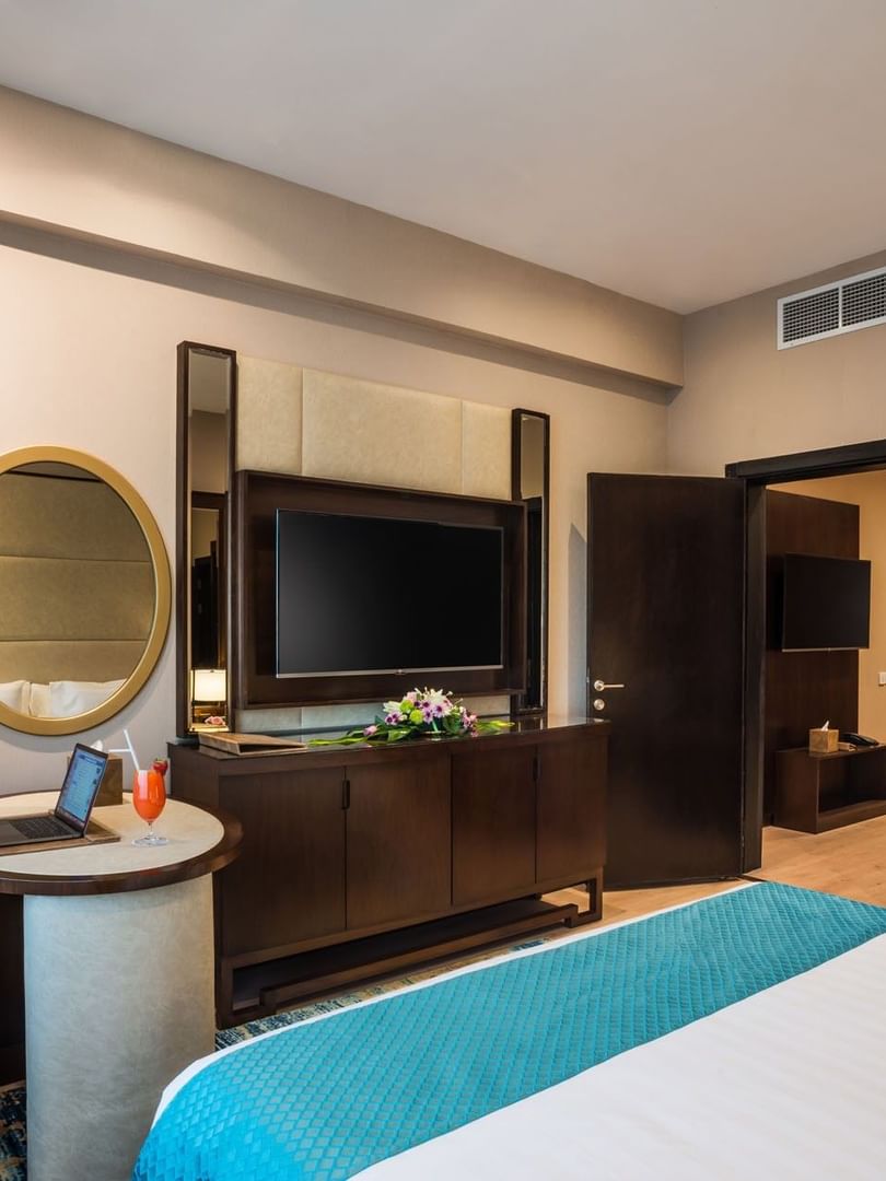 TV facing the bed with a work desk near the open door in Executive suite at Naviti By Warwick Dammam