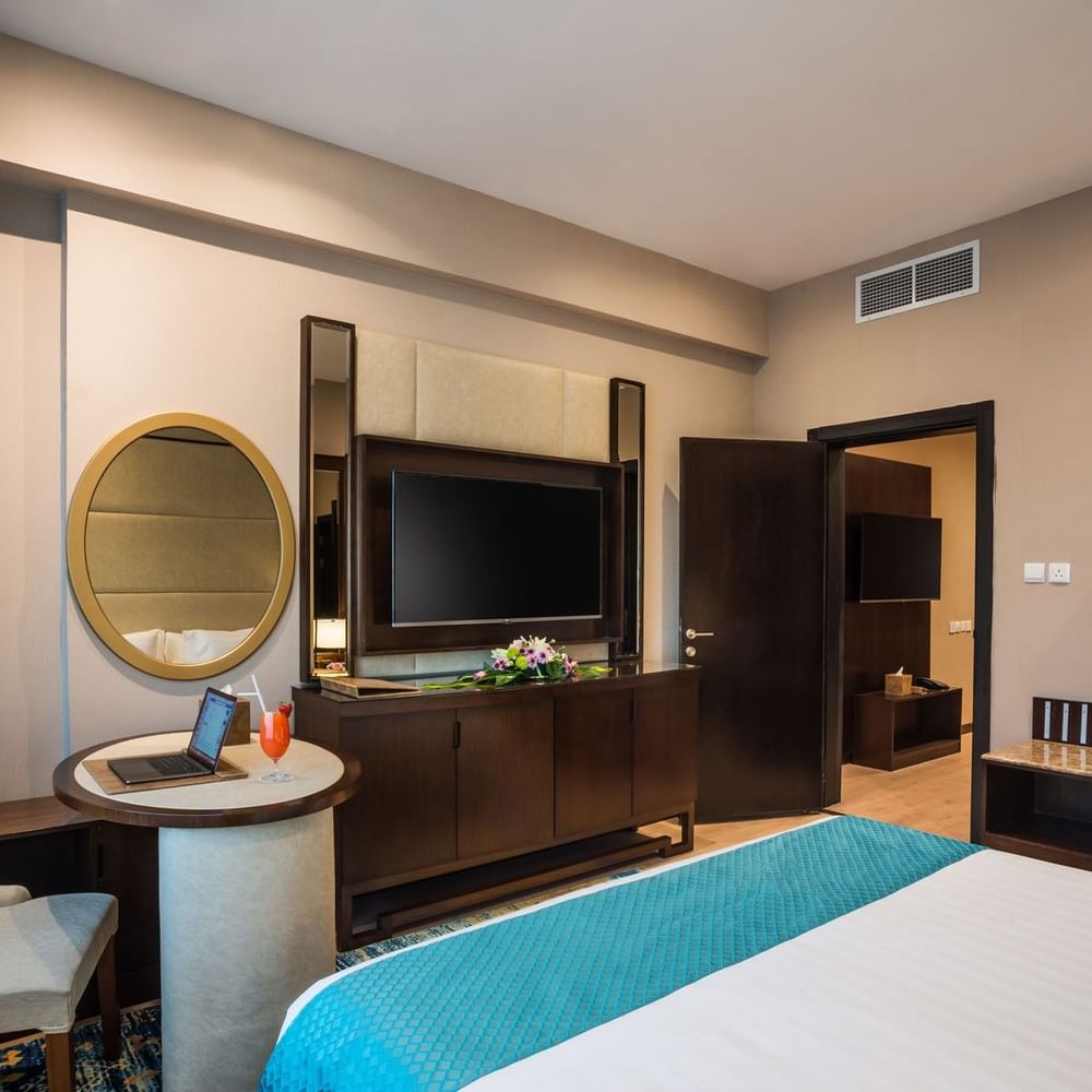 TV facing the bed with a work desk near the open door in Executive suite at Naviti By Warwick Dammam