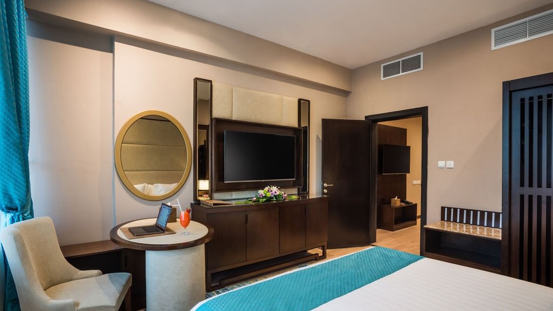 TV facing the bed with a work desk near the open door in Executive suite at Naviti By Warwick Dammam