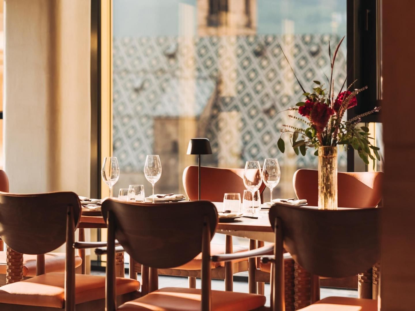 Eleganter Esstisch mit sechs Stühlen, einer Vase voller Blumen und einem Blick auf das Gebäude.