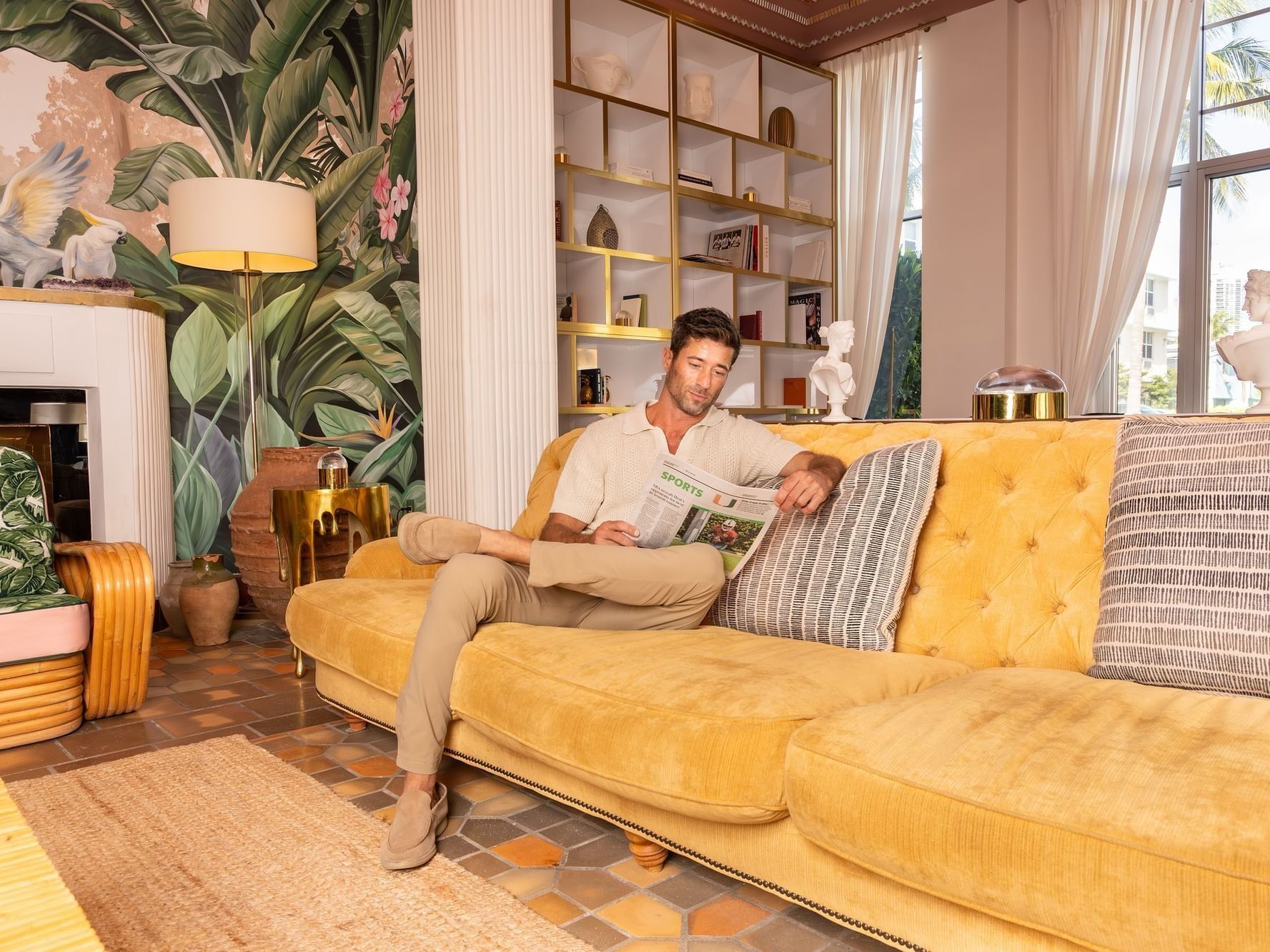 Man reading a newspaper on a couch in the lobby lounge area at The Savoy Hotel & Beach Club