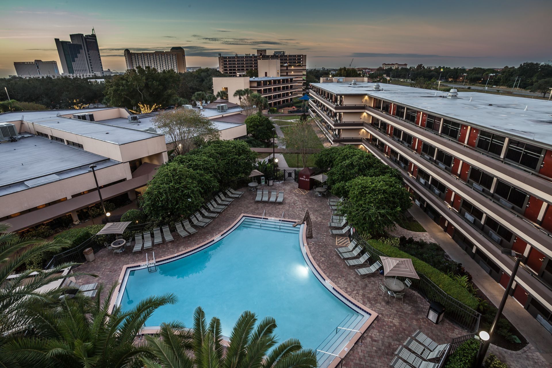 A pool and a glowing hotel overlooking the horizon of Orlando at sunset. 