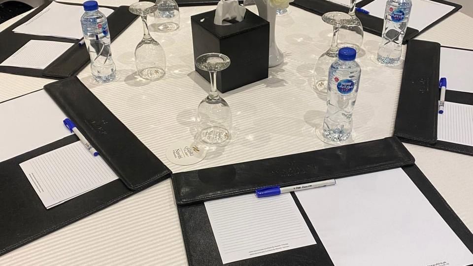 Round table set for a meeting, with pens, notepads, and a vase, in Crystal Meeting Room at Warwick Hotels and Resorts