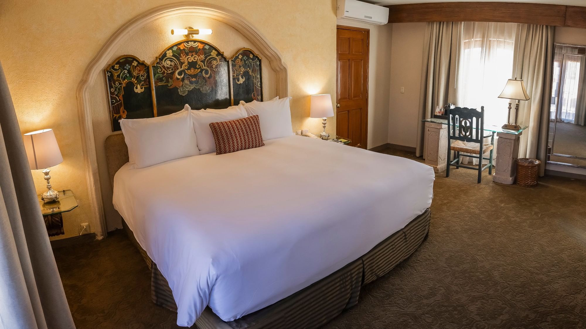 King Presidential Suite with ornate headboard, white linens, and seating area at Quinta Real Zacatecas