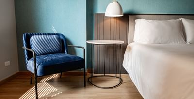 Accommodation in Bogota with a comfortable blue armchair and a bed with crisp white linens in a room at Habitel Hotel Select