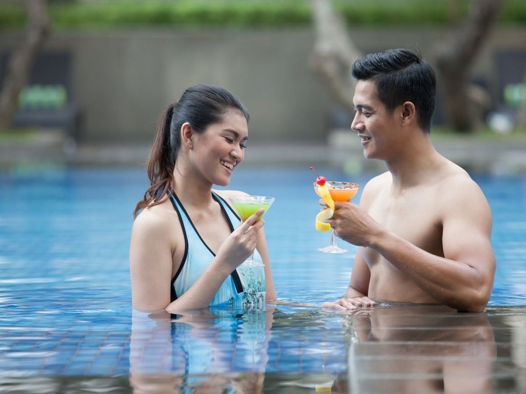 A couple enjoying drinks in the pool at Poolside Lounge and Deck in Royal Ambarrukmo Yogyyakarta