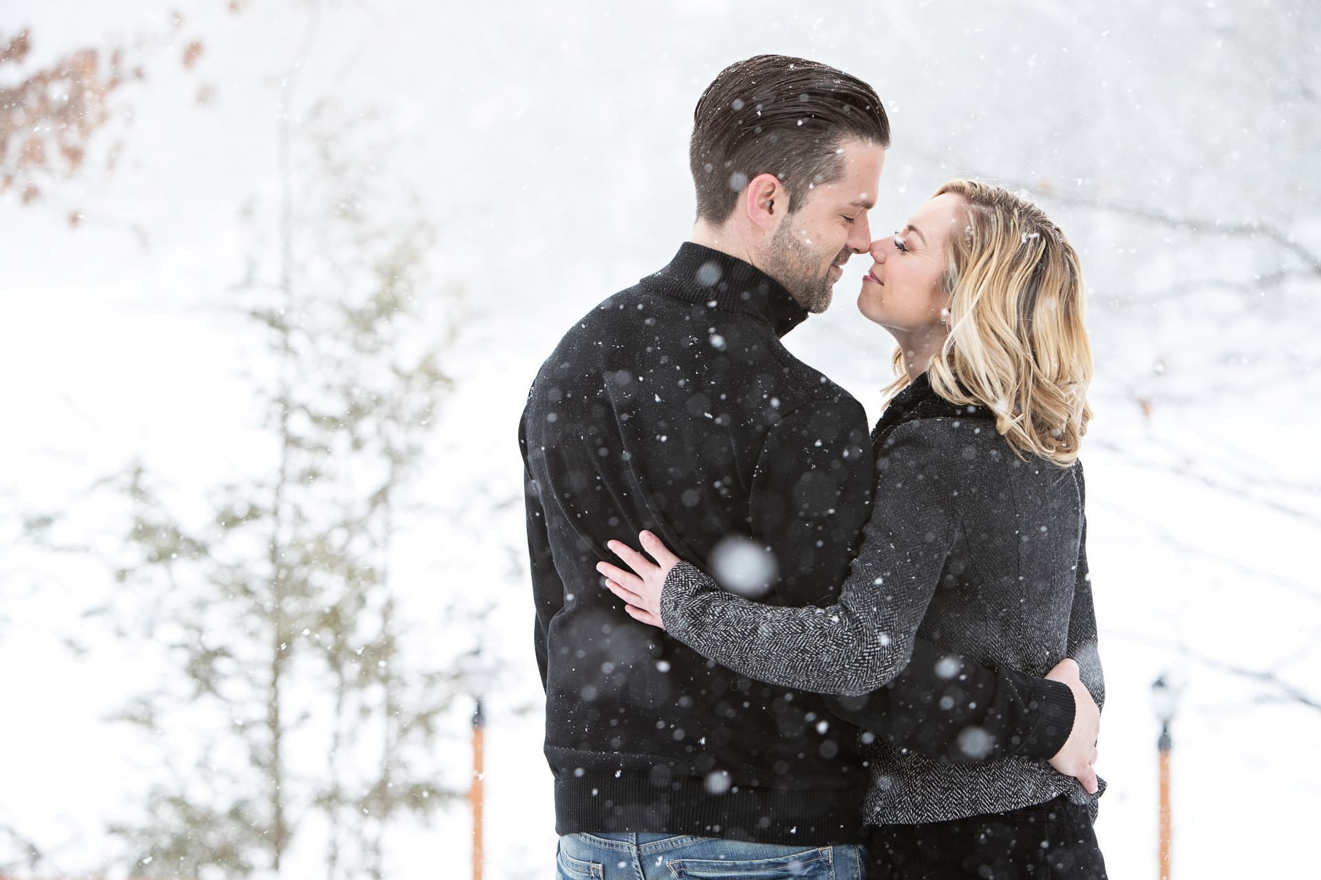 Beautiful couple embraces in a snowy landscape while snow gently falls around them at Cove Pocono Resorts