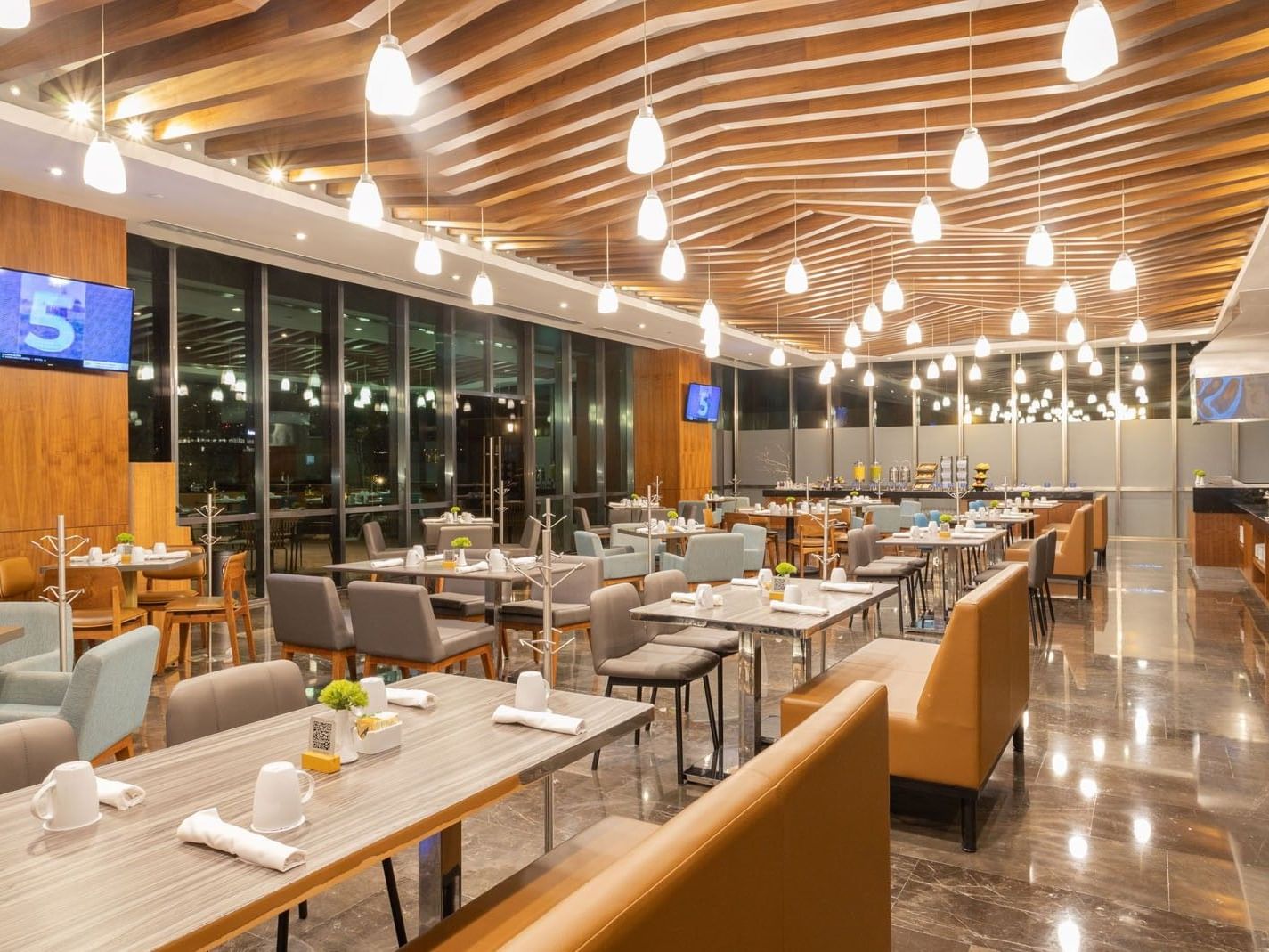 Distrito Regio room with tan booth seating and large windows showing the city at Camino Real Fashion Drive, Monterrey