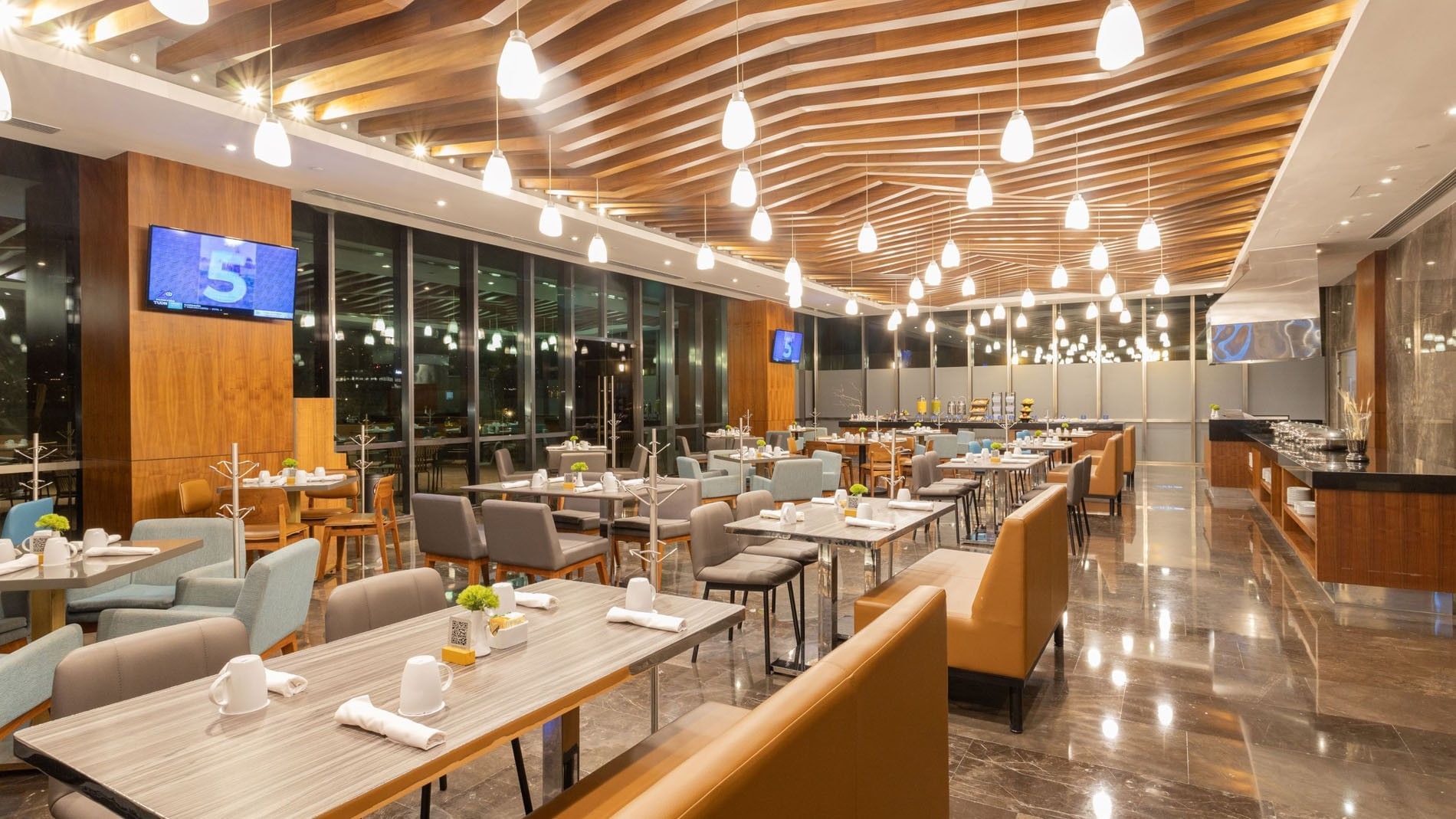 Distrito Regio room with tan booth seating and large windows showing the city at Camino Real Fashion Drive, Monterrey