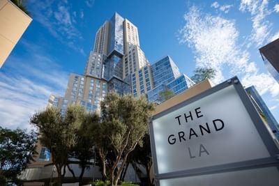 Tall building with sign reading The Grand LA at Aramark Ross