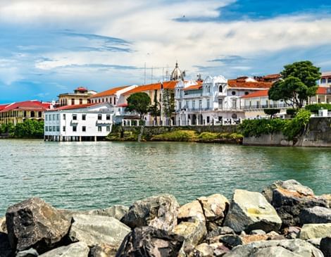 Casco Antiguo waterfront with white colonial buildings by the sunny sea, framed by rocks near Megapolis Hotel Panama